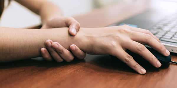 photograph of a woman holding her wrist due to chronic pain